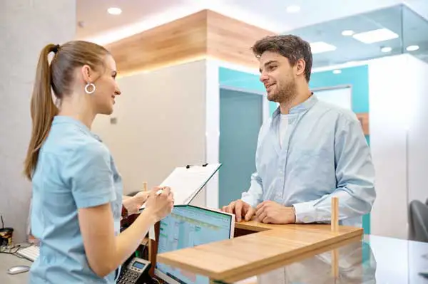 A receptionist helping a patient checkin A receptionist helping a patient checkin