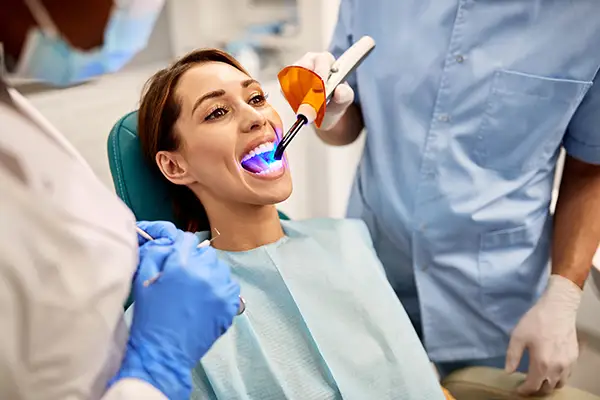 Dentist and assistant performing a dental bonding procedure on a female patient at East Portland Dentistry in Portland, OR